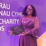 Mojisola Olateju smiling and holding her Volunteer of the Year award at the Welsh Charity Awards ceremony.