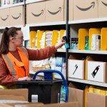 Amazon worker picking deodorant from warehouse shelves during donation campaign supporting Swansea’s Cwtch Mawr Multibank.