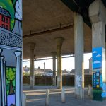 A wide view of colourful murals painted on concrete posts beneath the M4 flyover in Port Talbot.