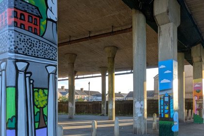A wide view of colourful murals painted on concrete posts beneath the M4 flyover in Port Talbot.