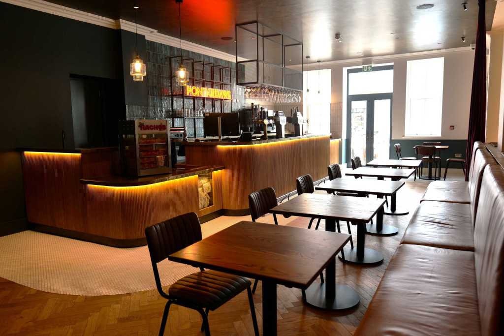 Café bar at Pontardawe Arts Centre with seating, bar area, and neon “Pontardawe” sign, part of the venue’s major refurbishment.