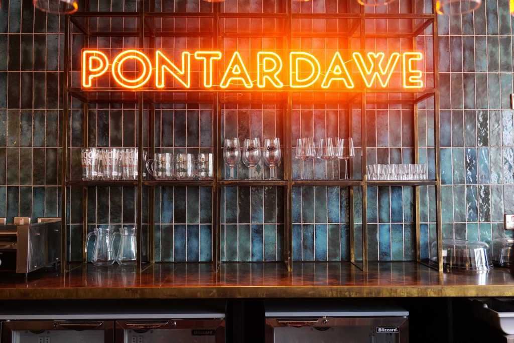 Neon “Pontardawe” sign above drinks glasses in the new café bar at Pontardawe Arts Centre, part of the venue’s redevelopment.