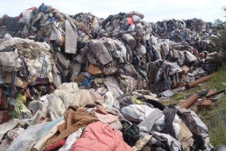 Photo shows huge mounds of baled textile waste illegally deposited at a Caerphilly farm, part of a case that led to a £322,500 repayment order.