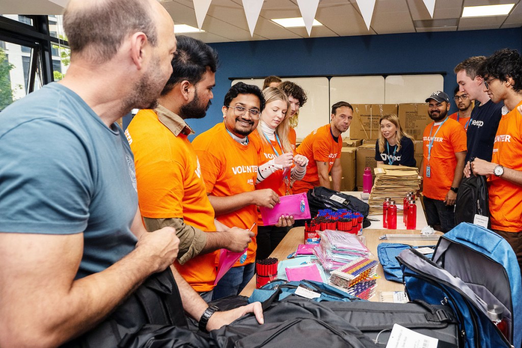 Close‑up of Amazon Swansea employees packing school backpacks with essential items for local children supported by Faith in Families.
