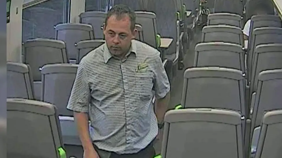 CCTV still of Nicholas McMurray walking through a train carriage.