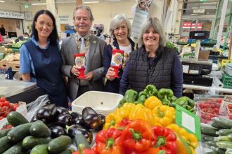 Lord Mayor of Swansea and her husband wearing chains of office at Get Fresh stall in Swansea Market with traders, holding collection tins for the Just A Pound cancer appeal.