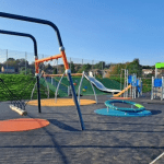 Wide view of Parc Gwernfadog playground with multiple new play structures.