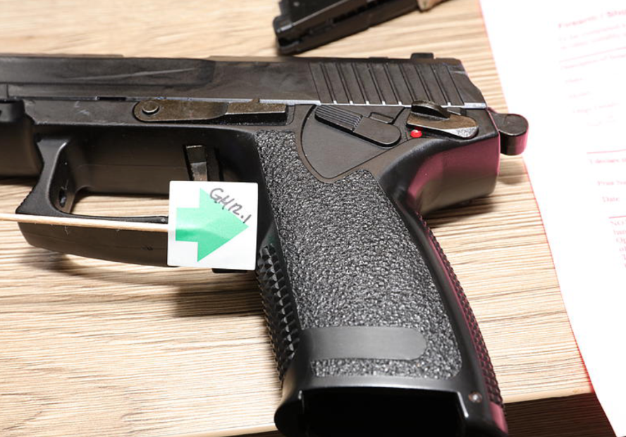 A gun photographed with an evidence label during the police investigation.