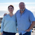 Ruth Jones and Steve Speirs stand arm in arm by the sea in Wales, promoting their upcoming BBC Wales comedy about friendship and life in middle age.