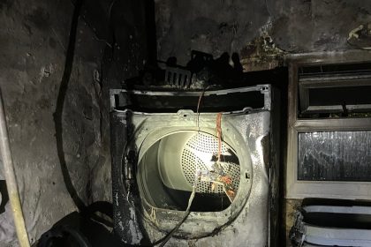 Burnt tumble dryer inside blackened outbuilding following fire in Penlan, Swansea.