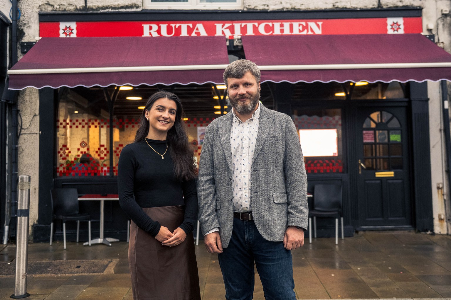 Front of Ruta Kitchen café in Swansea with Charlotte Price, Development Bank of Wales, and co‑founder Vladimir Pavliiciuc.