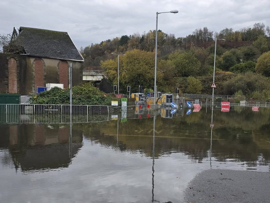 View from the Cwmbwrla side of the railway bridge showing Cwmbwrla roundabout under floodwater with pumping equipment in the distance.