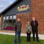 Three councillors standing outside Canolfan Llwynhendy, a newly renovated community hub in Llwynhendy.