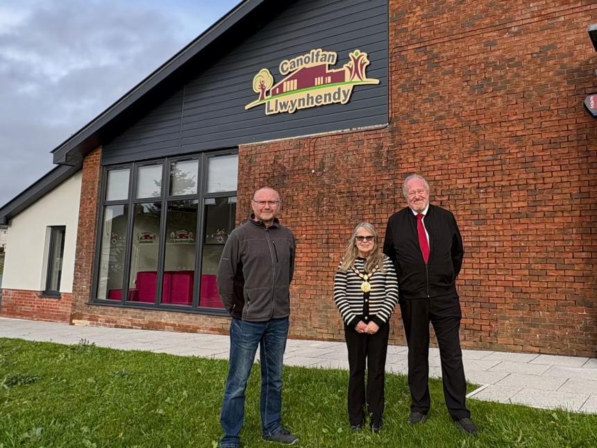 Three councillors standing outside Canolfan Llwynhendy, a newly renovated community hub in Llwynhendy.