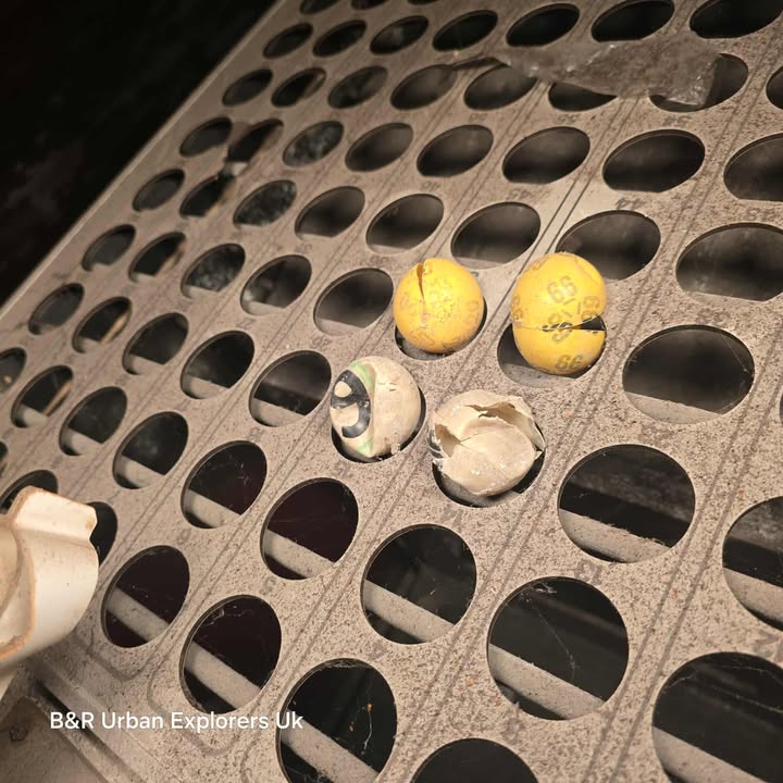 Yellow and white numbered bingo balls on a perforated metal rack inside Swansea’s abandoned Elysium Theatre.