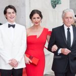 Catherine Zeta‑Jones in a red dress on the red carpet outside Brangwyn Hall, with Michael Douglas and their son Dylan, attending her Freedom of the City ceremony in Swansea.
