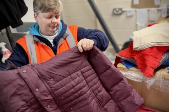 Volunteer sorting winter clothing at Cwtch Mawr Multibank in Swansea