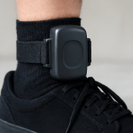 Closeup of a GPS ankle monitoring tag worn over a sock and shoe.