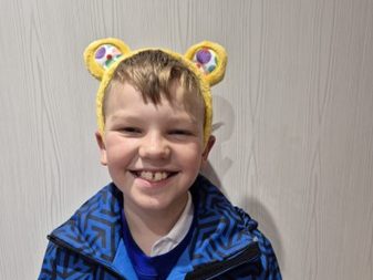 Dewi, a 10‑year‑old boy from Swansea, smiling in Pudsey Bear ears before his BBC Children in Need Choir performance.