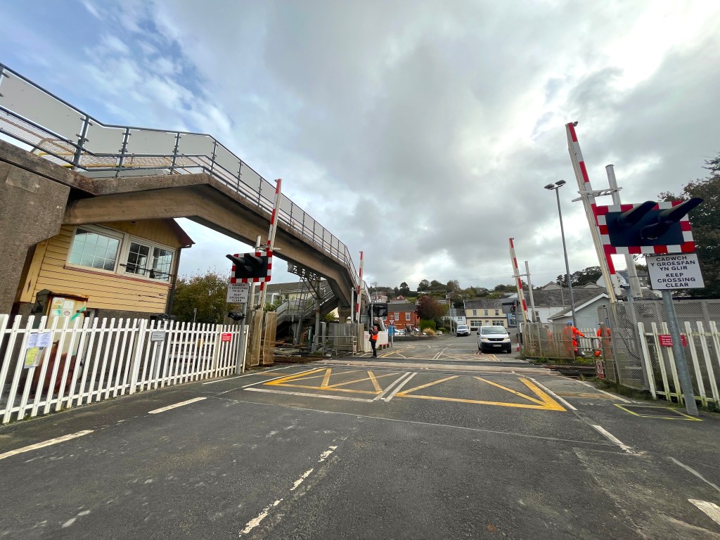 Ferryside railway level crossing with barriers and road markings.