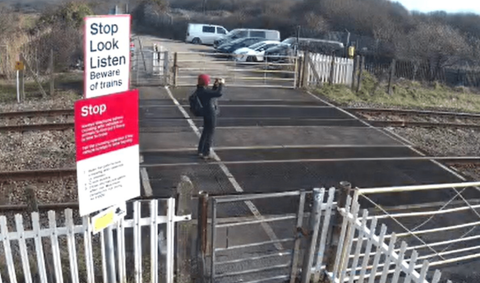 Person standing on railway tracks at Port Talbot crossing photographing approaching train.
