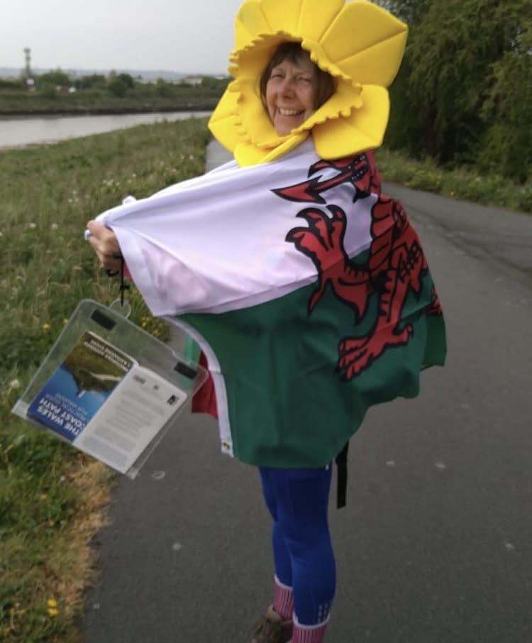 Janet Baldock wearing a daffodil costume and Welsh flag while promoting the Wales Coast Path