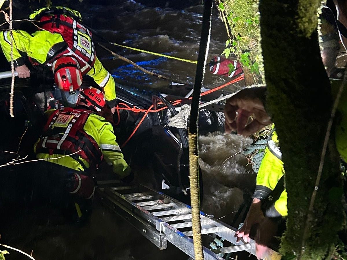 Rescue crews using ladders to reach a car trapped in floodwater during the Lampeter flooding incident.
