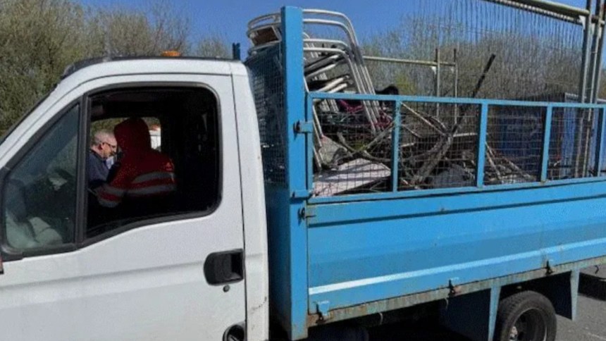 Side view of a Transit tipper truck. Leon Medlam, wearing an orange hi‑vis jacket, is seated in the driver’s seat speaking to an enforcement officer at the window.