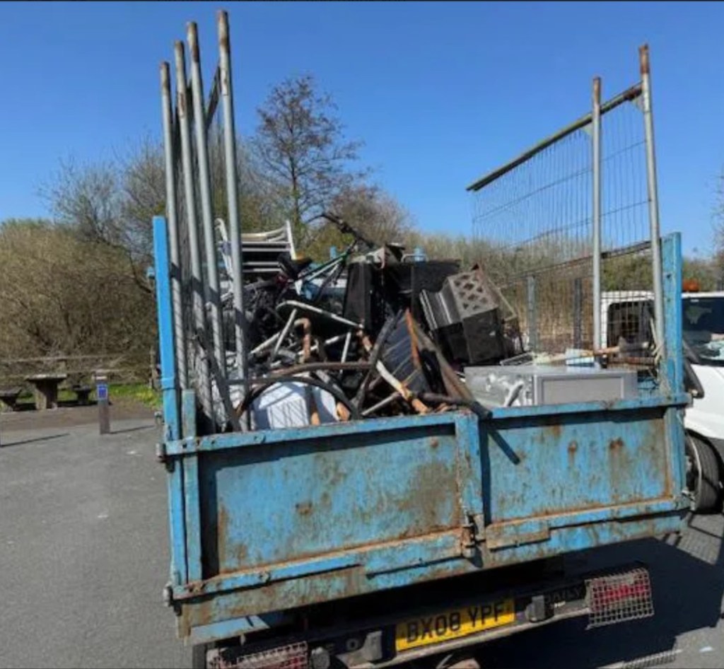 Rear view of a Transit tipper truck showing large amounts of scrap metal loaded in the tipper bed.