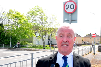 Council leader Steve Hunt standing beside a 20mph road sign in Neath Port Talbot.