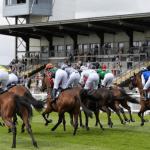 Horses and jockeys racing over hurdles at Ffos Las Racecourse in Carmarthenshire, Wales.