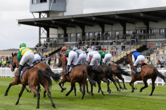Horses and jockeys racing over hurdles at Ffos Las Racecourse in Carmarthenshire, Wales.