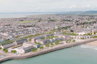Aerial view of Porthcawl seafront with marina, beach, and amusement rides.