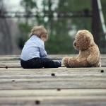 boy sitting with brown bear plush toy on selective focus photo