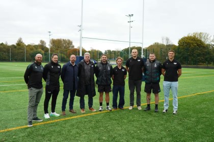 Ten individuals from Ospreys and Swansea University standing on a rugby pitch at St Helen’s, marking the launch of their new elite rugby development partnership.