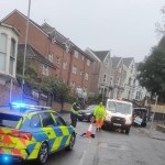 Police and utility workers at the scene of a sinkhole on Bryn-y-Mor Road, Swansea, with traffic cones and vehicles blocking the road.