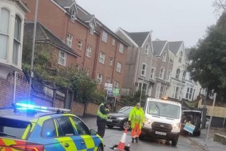 Police and utility workers at the scene of a sinkhole on Bryn-y-Mor Road, Swansea, with traffic cones and vehicles blocking the road.