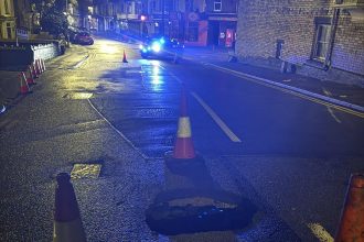 Sinkhole reopens on Brynymor Road, Swansea, with police lights and cones marking closure.