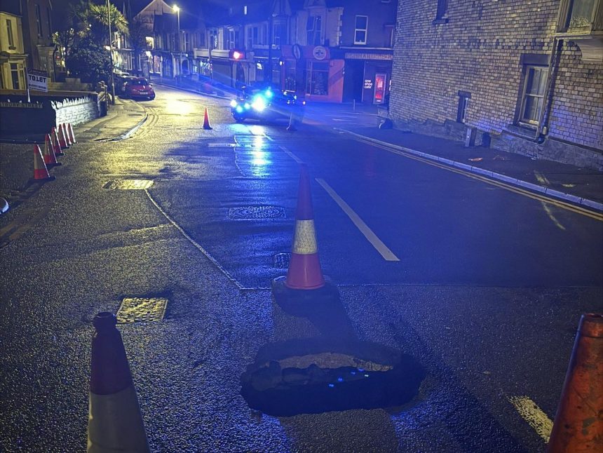 Sinkhole reopens on Brynymor Road, Swansea, with police lights and cones marking closure.