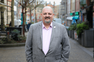 Andrew Douglas standing on Swansea’s Wind Street, with hospitality venues visible behind him.