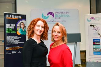 Amy Seppman and Cherrie Bija smiling at a Swansea Bay Business Club event with Help to Grow and sponsor banners.