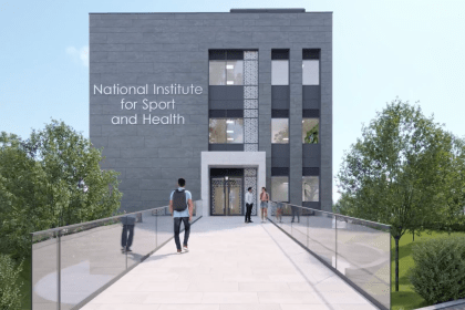 Modern building labeled National Institute for Sport and Health with landscaped entrance and glass walkway.