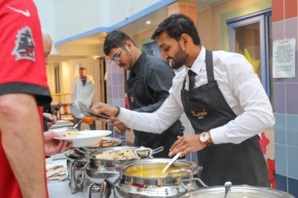 Rasoi chefs serving Indian food to attendees at a Swansea homelessness support event.