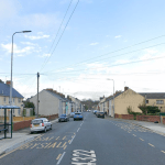 Residential street in Pembroke Dock with bus stops, parked cars, and semi-detached houses on Laws Street.