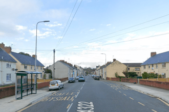 Residential street in Pembroke Dock with bus stops, parked cars, and semi-detached houses on Laws Street.