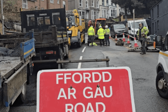 Road closed sign with highways crews at Brynymor Road sinkhole site.