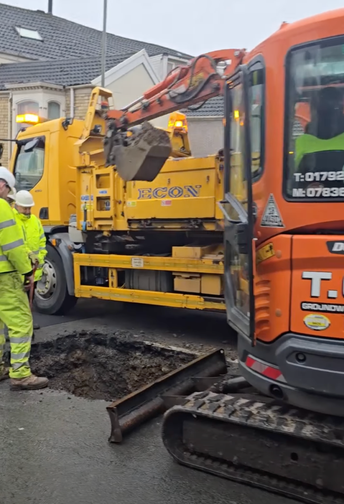 Excavator bucket lifting debris from Brynymor Road sinkhole.