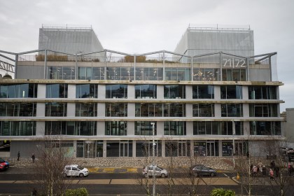 Exterior of 71/72 Kingsway building in Swansea with glass facade and visible signage.