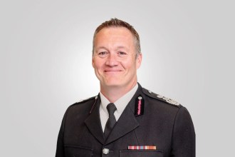 Craig Flannery in fire service uniform with service ribbons, photographed against a plain grey background.
