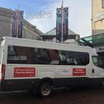 Shopper Hopper minibus outside Quadrant Shopping Centre in Swansea, with bilingual signage and nearby shops.